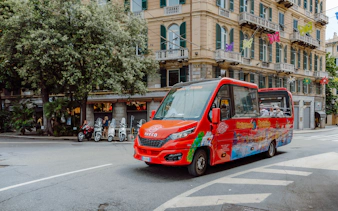City sightseeing bus driving through urban street with historic buildings.