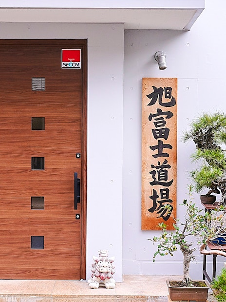Entrance to sumo dojo in Koto City with bonsai trees and traditional signage.