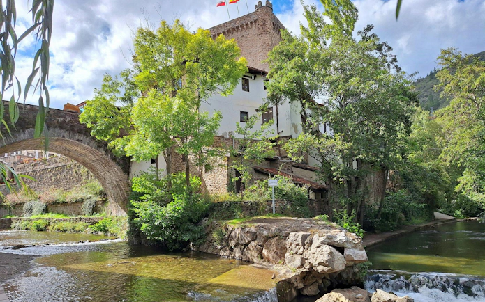 Stone bridge and medieval tower by a river in Potes, Cantabria, Spain.