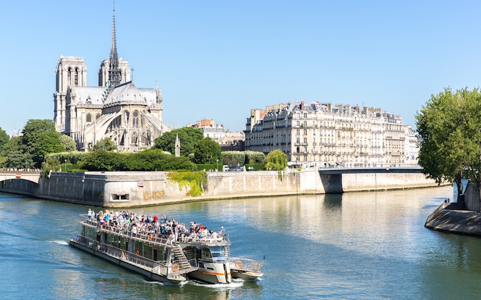 Cruise boat on the Seine River near Notre Dame Cathedral in Paris.