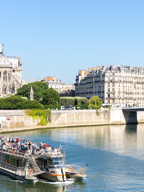 Cruise boat on the Seine River near Notre Dame Cathedral in Paris.