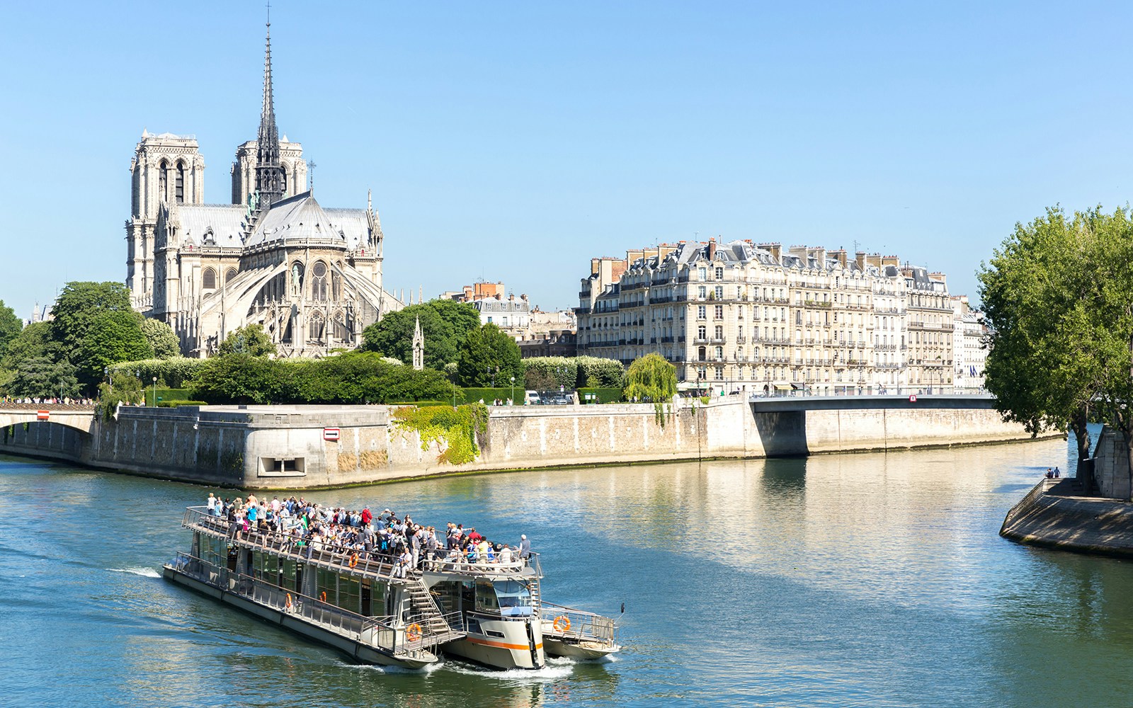 Seine River cruise boat near Notre Dame Cathedral, Paris, with audio guide.