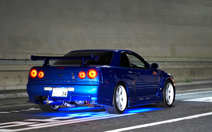 Blue Nissan Skyline R34 with neon lights at Daikoku PA car meeting.