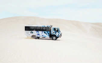 4WD vehicle driving on sand dunes during Lancelin sandboarding adventure.