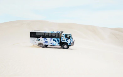 4WD vehicle driving on sand dunes during Lancelin sandboarding adventure.