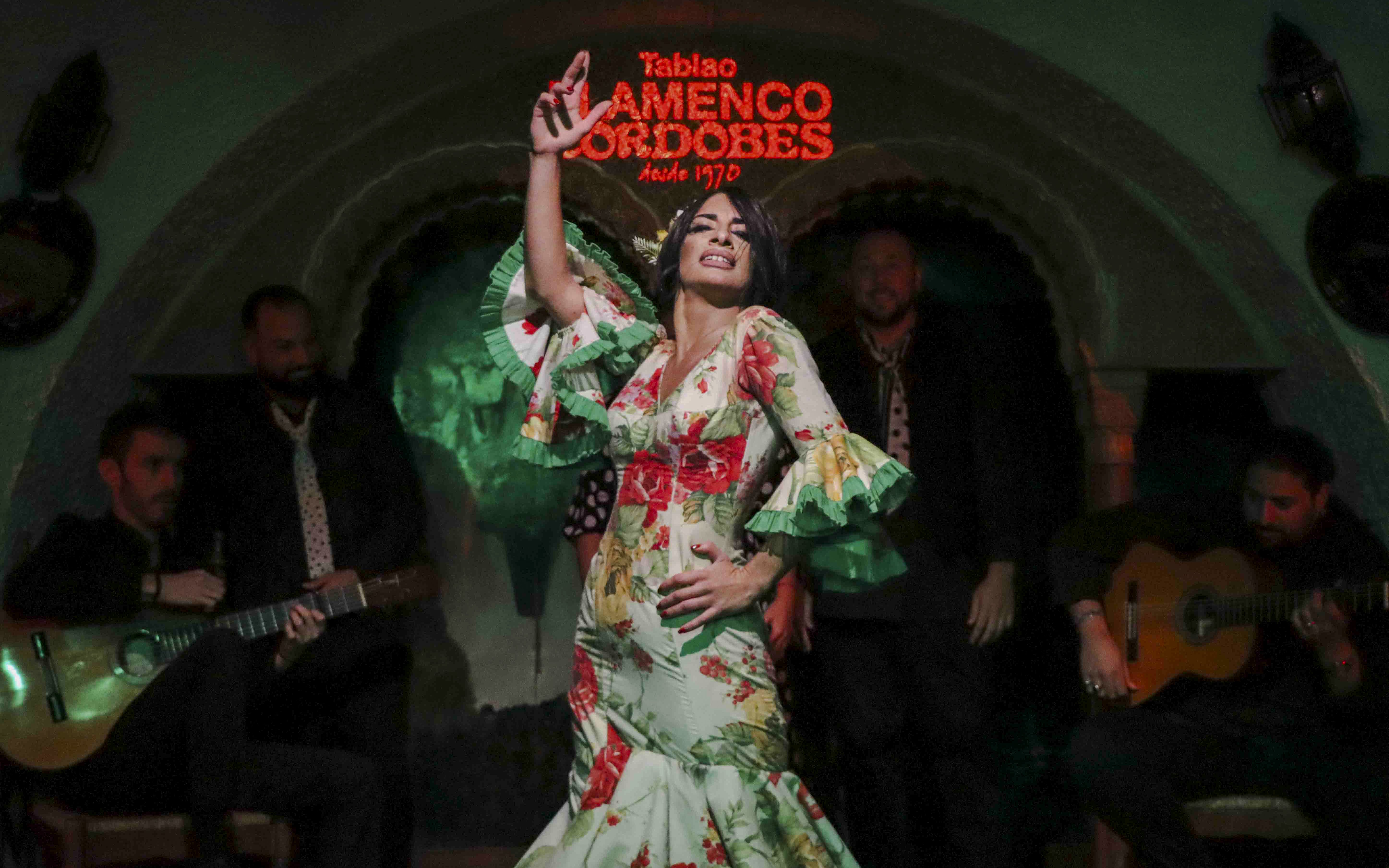 Flamenco dancer performing at Tablao Cordobes with musicians in the background.