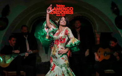 Flamenco dancer performing at Tablao Cordobes with musicians in the background.