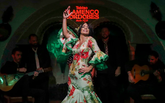 Flamenco dancer performing at Tablao Cordobes with musicians in the background.