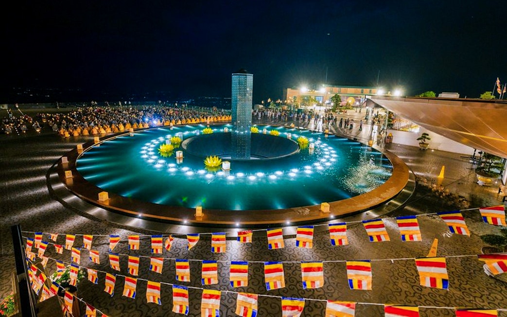 Colorful flags and illuminated fountain at night, Sun World Ba Den Mountain, Vietnam.