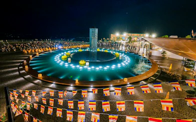 Colorful flags and illuminated fountain at night, Sun World Ba Den Mountain, Vietnam.