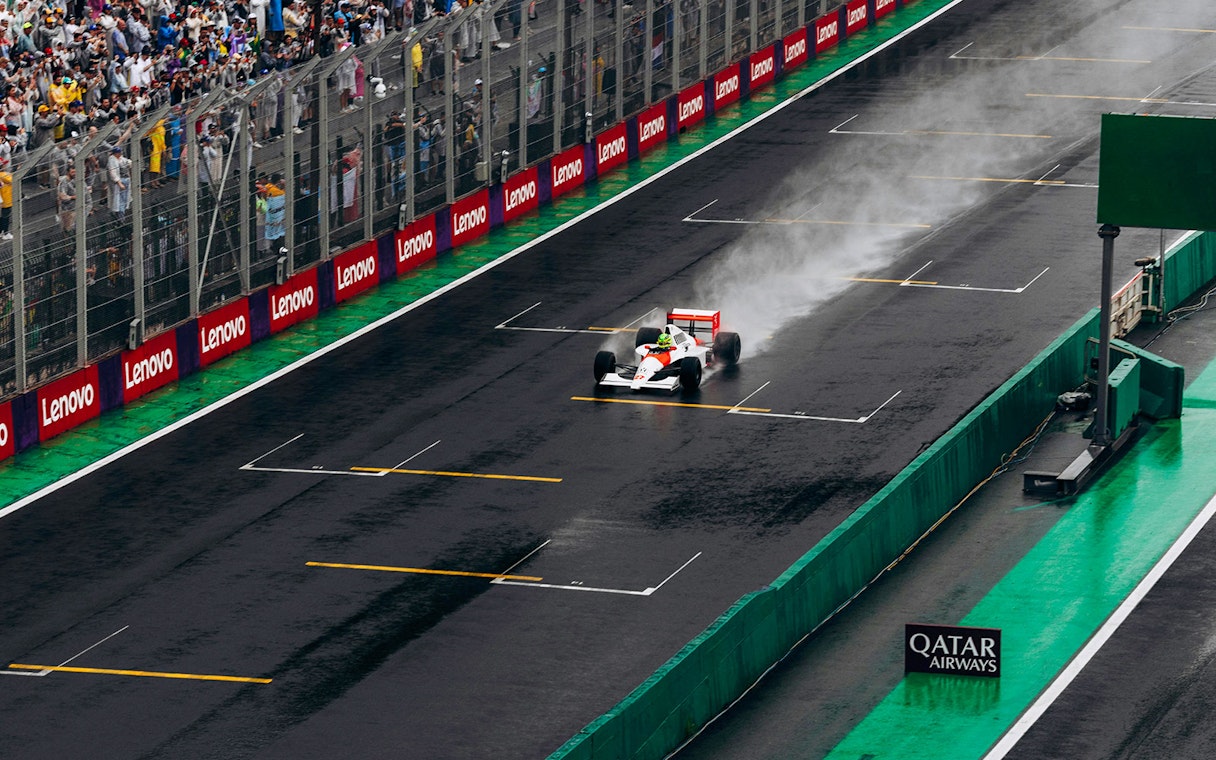 Formula 1 car racing on a wet track in Qatar with spectators in the background.