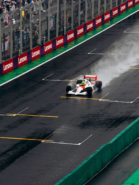 Formula 1 car racing on a wet track in Qatar with spectators in the background.