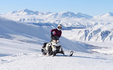 Snowmobile rider on snowy mountain trail, Fairbanks, Alaska.