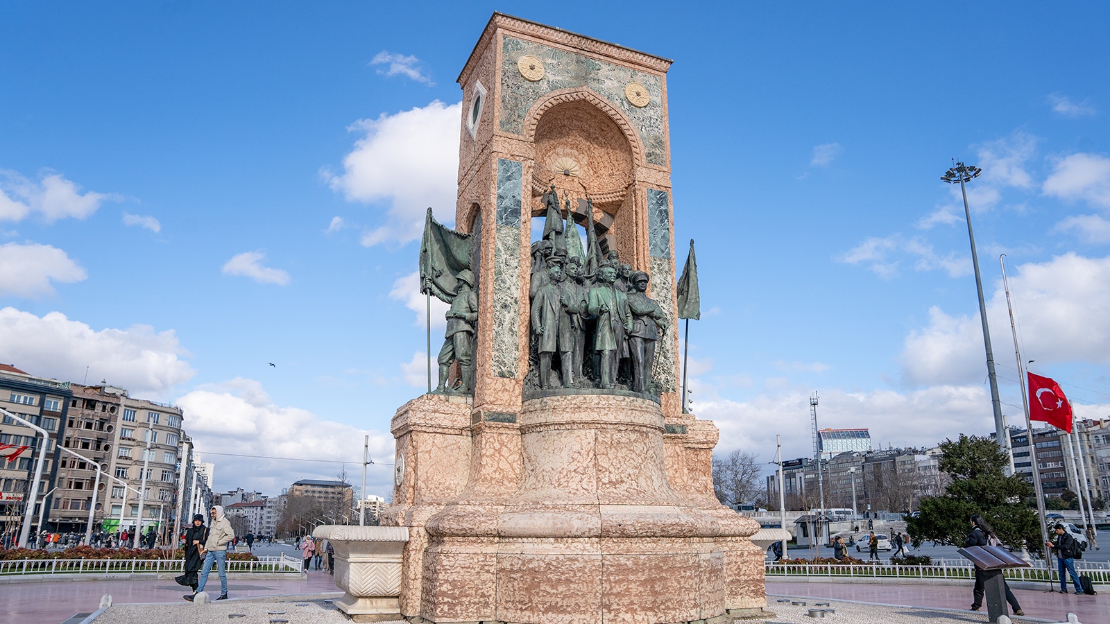 Republic Monument at Taksim Square, Istanbul, with people gathered around as seen from HOHO Bus.