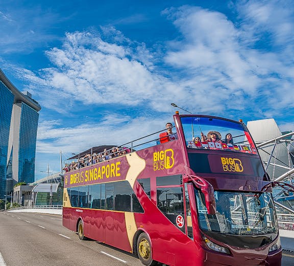 Open-top Big Bus Singapore tour passing Marina Bay Sands.