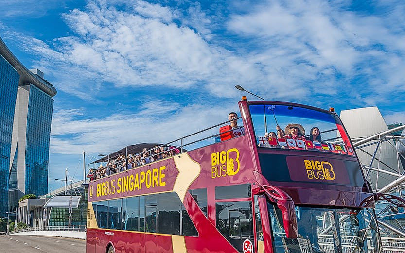 Open-top Big Bus Singapore tour passing Marina Bay Sands.