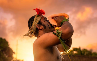 Warrior blowing conch shell at sunset during Mauka Warriors Luau.