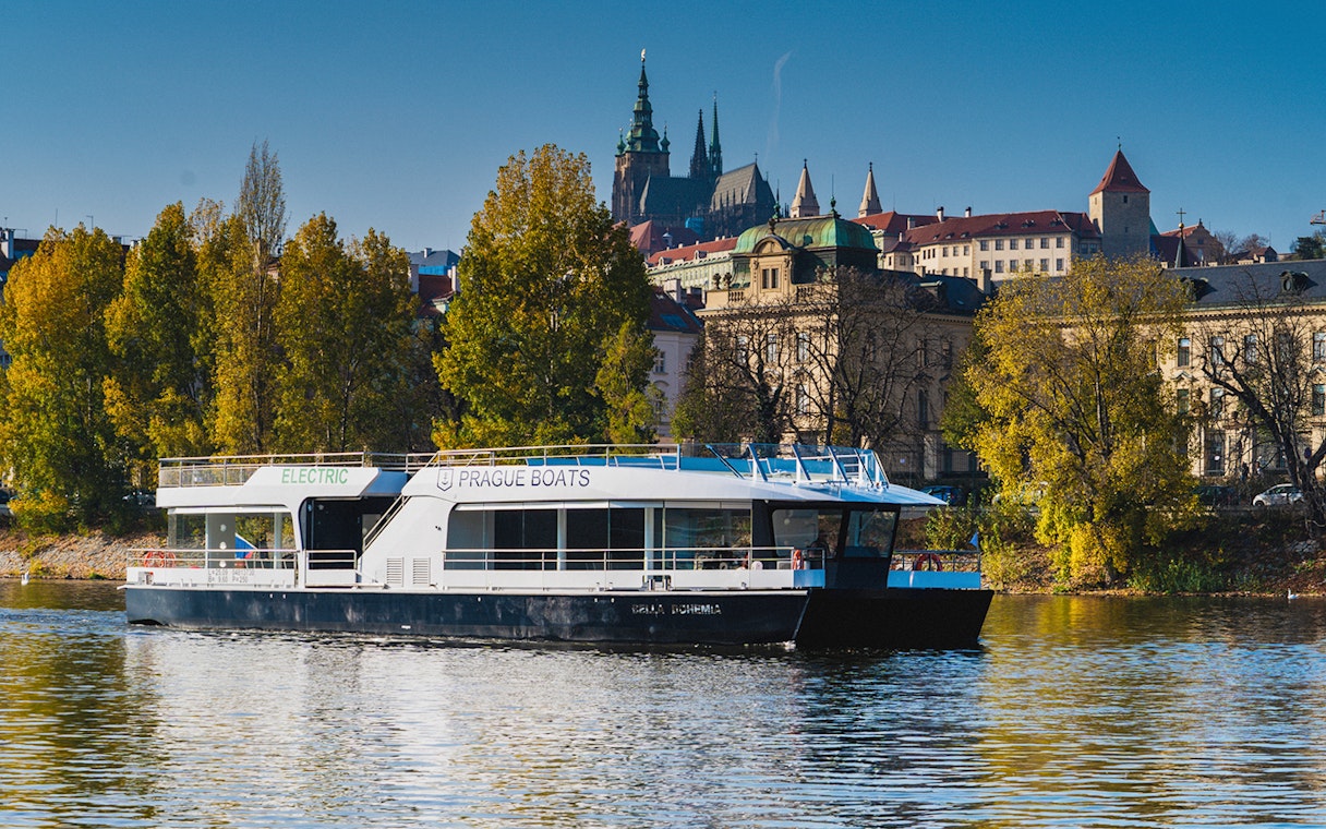 Prague boat on Vltava River with Prague Castle in the background.