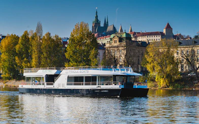 Prague boat on Vltava River with Prague Castle in the background.