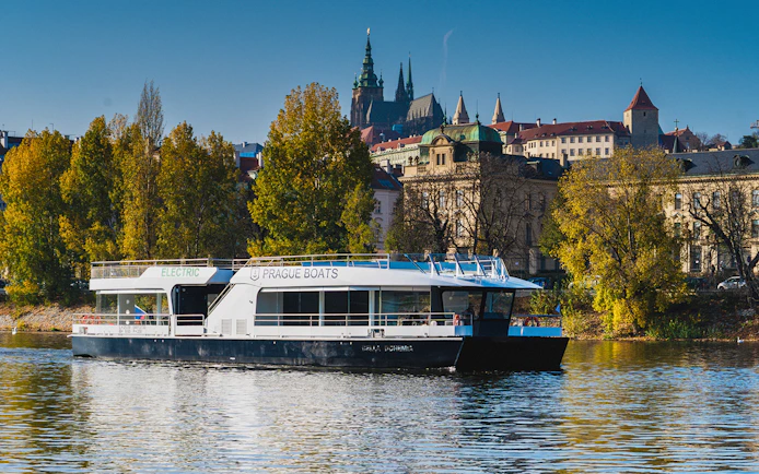 Prague boat on Vltava River with Prague Castle in the background.