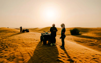 ATV riders on Dubai desert safari at sunset.
