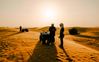 ATV riders on Dubai desert safari at sunset.