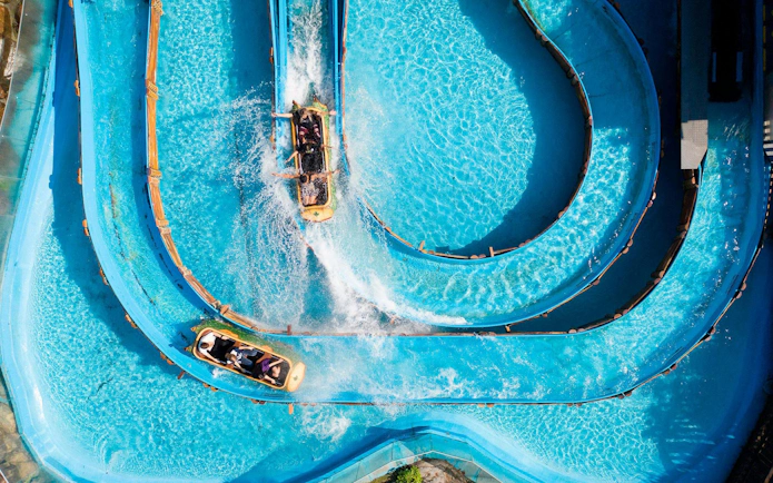 Water slide at Beto Carrero World with people riding in a raft on a winding blue track.