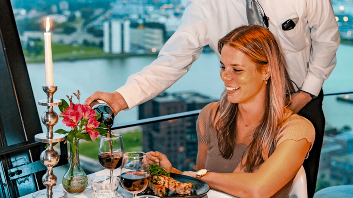 Server pouring wine at a table with a view at Euromast dining experience.