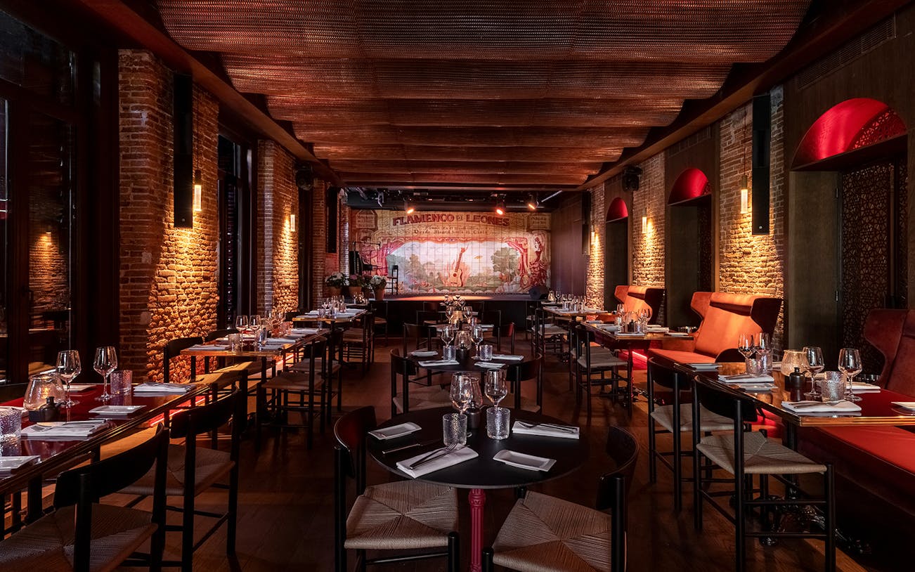 Flamenco de Leones venue with tables set for dining, stage in background, Madrid.