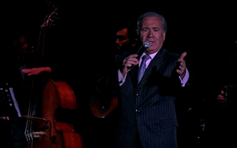 Singer performing at Homero Manzi Tango Show with double bass in background.