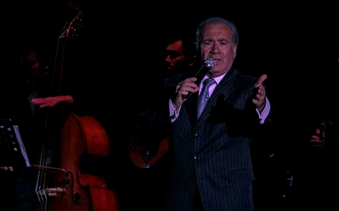 Singer performing at Homero Manzi Tango Show with double bass in background.