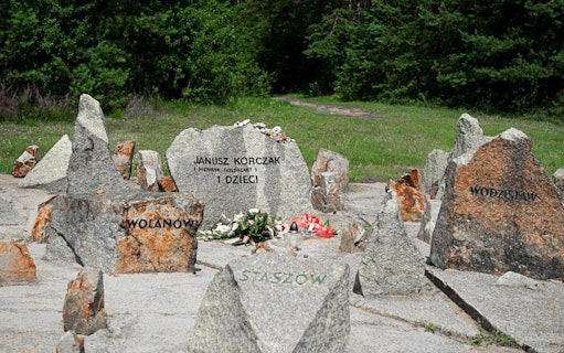 Memorial stones at Treblinka Extermination Camp with names and flowers.