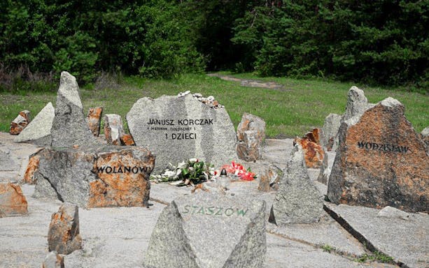 Memorial stones at Treblinka Extermination Camp with names and flowers.