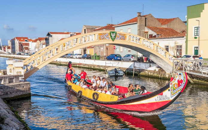 Moliceiro boat tour under bridge in Aveiro canal, Portugal.
