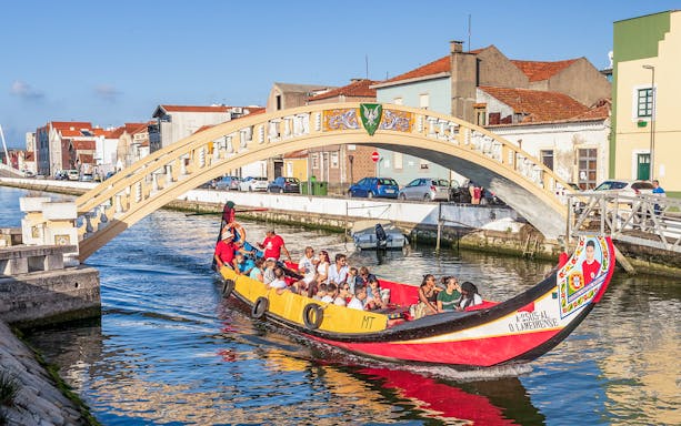 Moliceiro boat tour under bridge in Aveiro canal, Portugal.