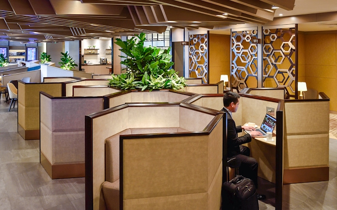 Cubicles in Plaza Premium Lounge at Singapore airport with a person working on a laptop.
