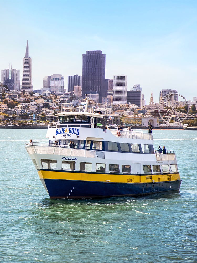 Blue and Gold Fleet ferry cruising in San Francisco Bay with city skyline in the background.