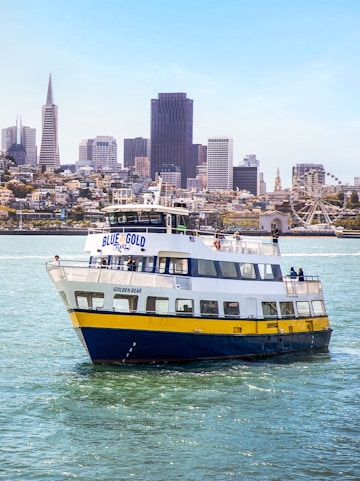 Blue and Gold Fleet ferry cruising in San Francisco Bay with city skyline in the background.