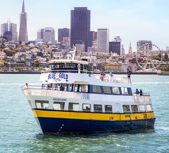 Blue and Gold Fleet ferry cruising in San Francisco Bay with city skyline in the background.