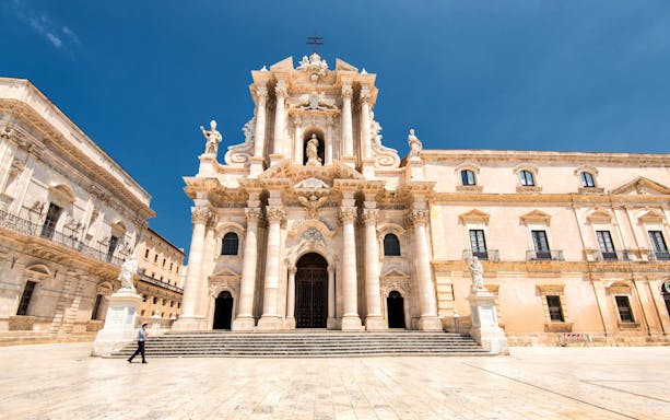 Baroque facade of the Cathedral of Syracuse in Ortigia, Sicily, under a clear blue sky.