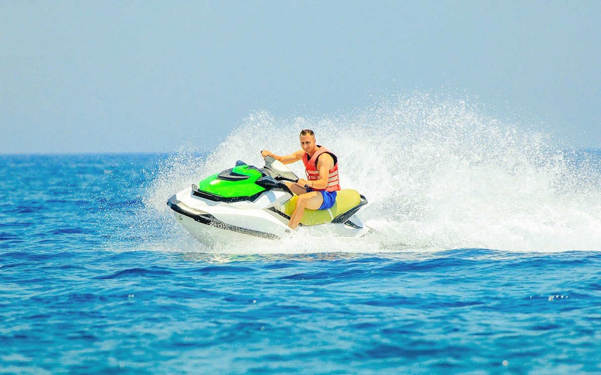 Tourist riding a jetski on open water.