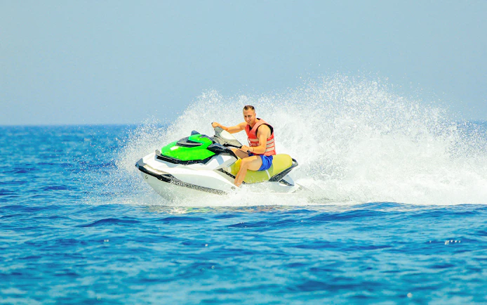 Tourist riding a jetski on open water.
