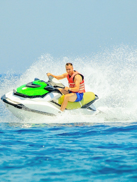 Tourist riding a jetski on open water.