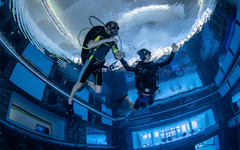 Scuba divers exploring Deep Dive Dubai's underwater city.