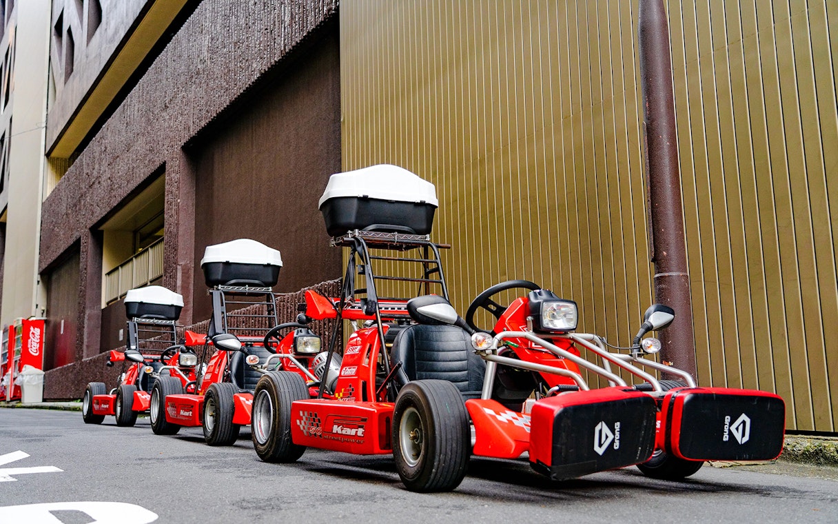 Red go-karts lined up on a street in Akihabara, Tokyo, ready for a driving experience.