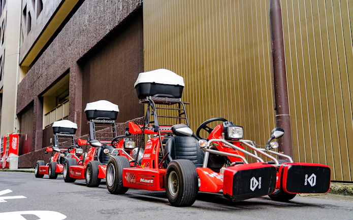 Red go-karts lined up on a street in Akihabara, Tokyo, ready for a driving experience.