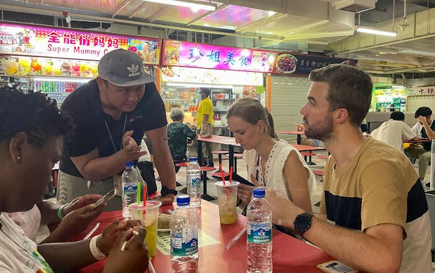 Group enjoying local food at a hawker center during Bike and Bites Food Tour.