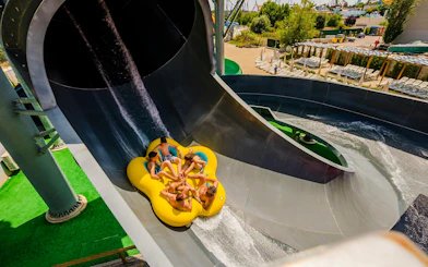 Group on a yellow raft sliding down a water slide at Parque Warner Beach.