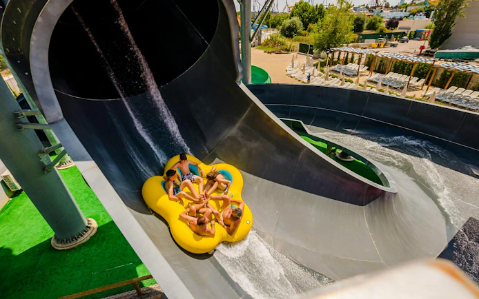 Group on a yellow raft sliding down a water slide at Parque Warner Beach.