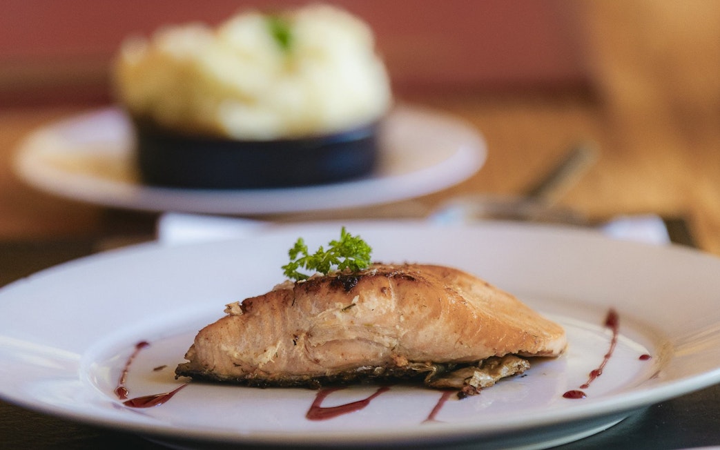 Cooked salmon fillet with mashed potatoes on a white plate.